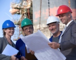 3 mannen en een vrouw met helm op bouwwerf bekijken plan